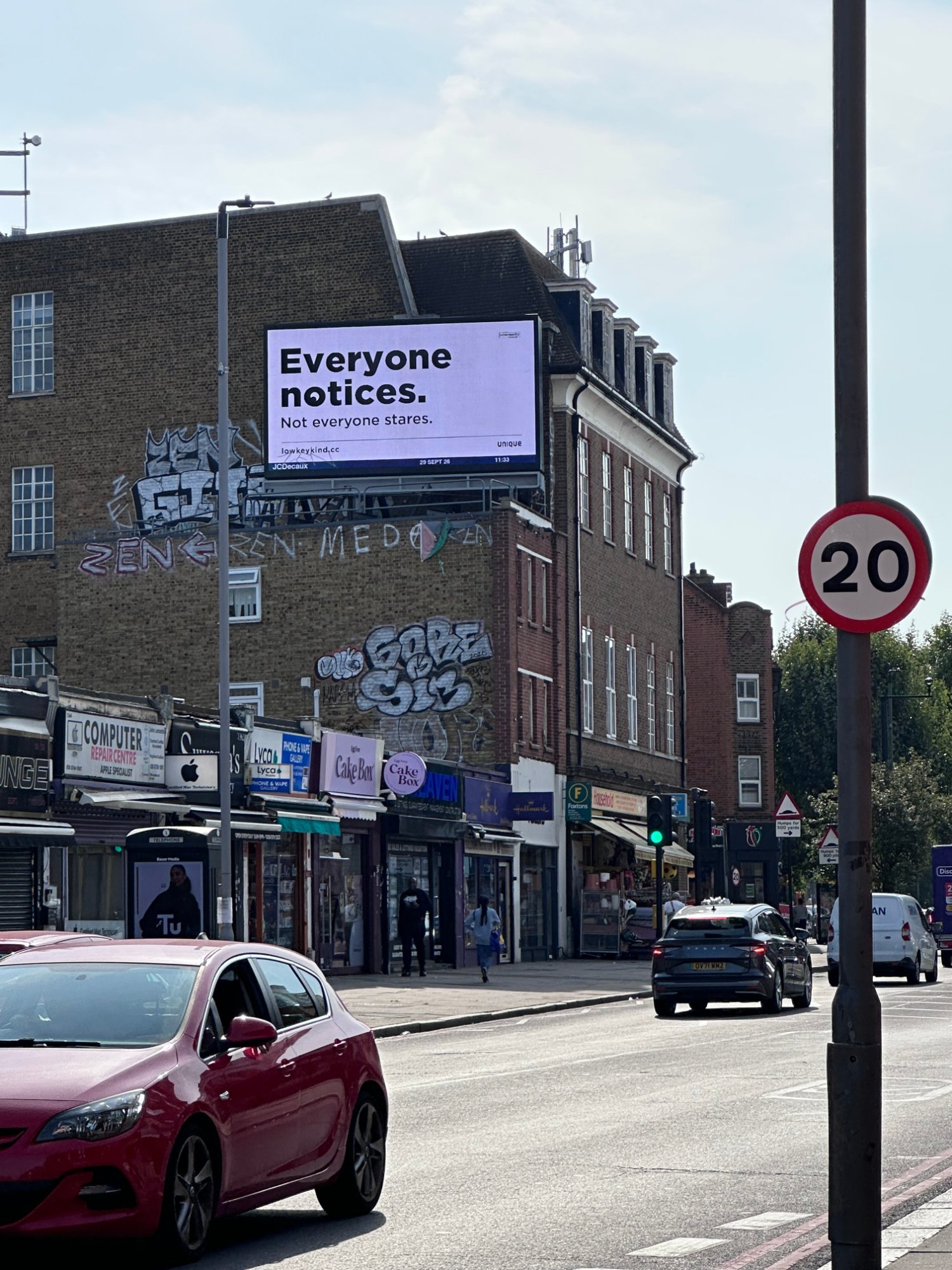Low-key kind digital billboard above a row of shops in Norbury, London
